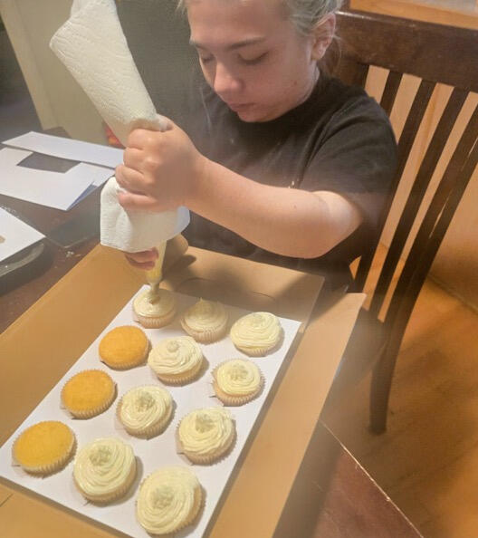 Rylee piping frosting onto homemade cookies Rylee piping vanilla frosting onto a tray of homemade cookies